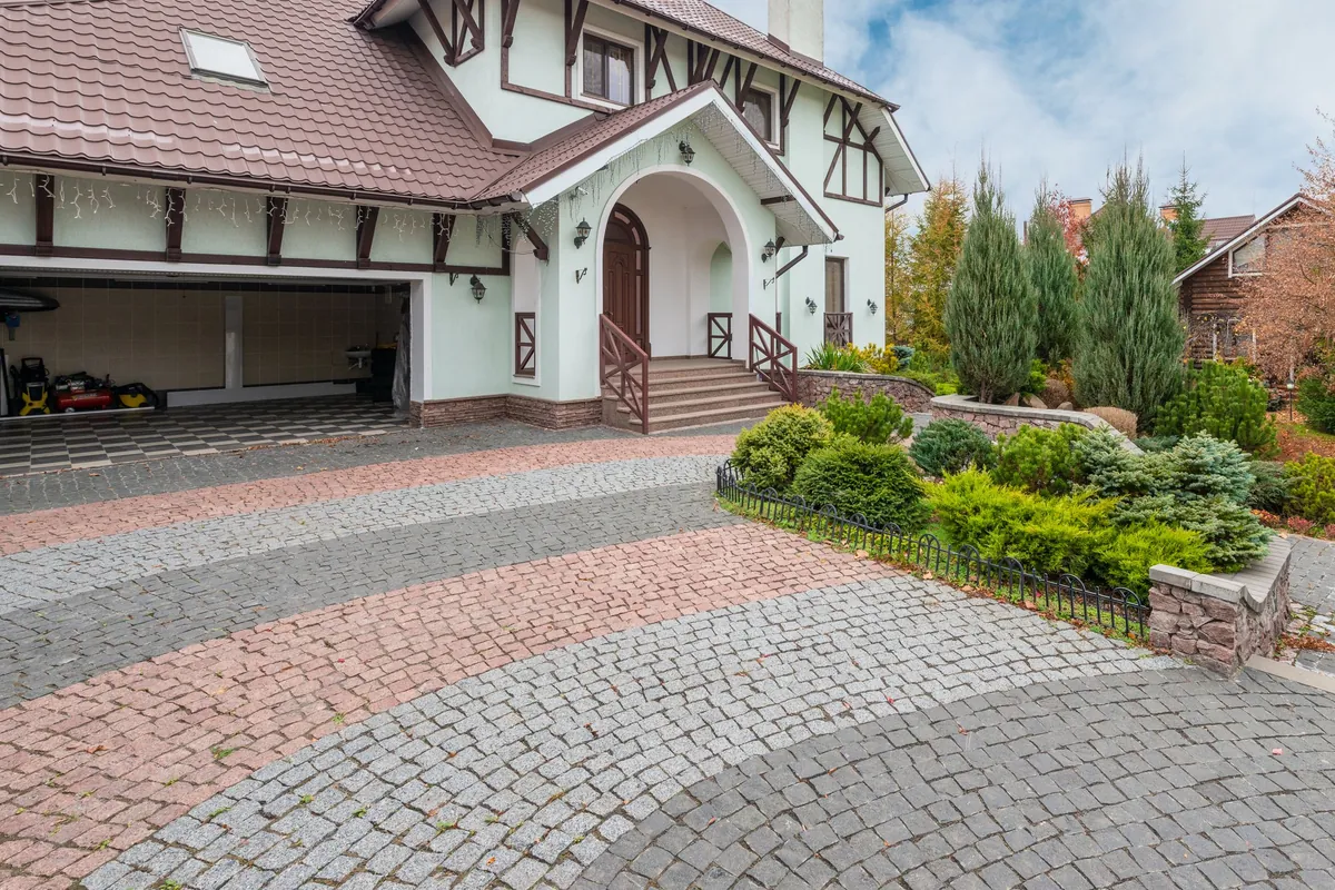 Curved paver driveway in two tones leading to a garage